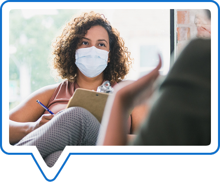 A one-to-one therapy session with participants wearing face coverings.